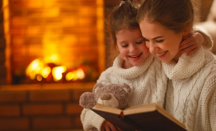 Mother and daughter reading by the fireplace